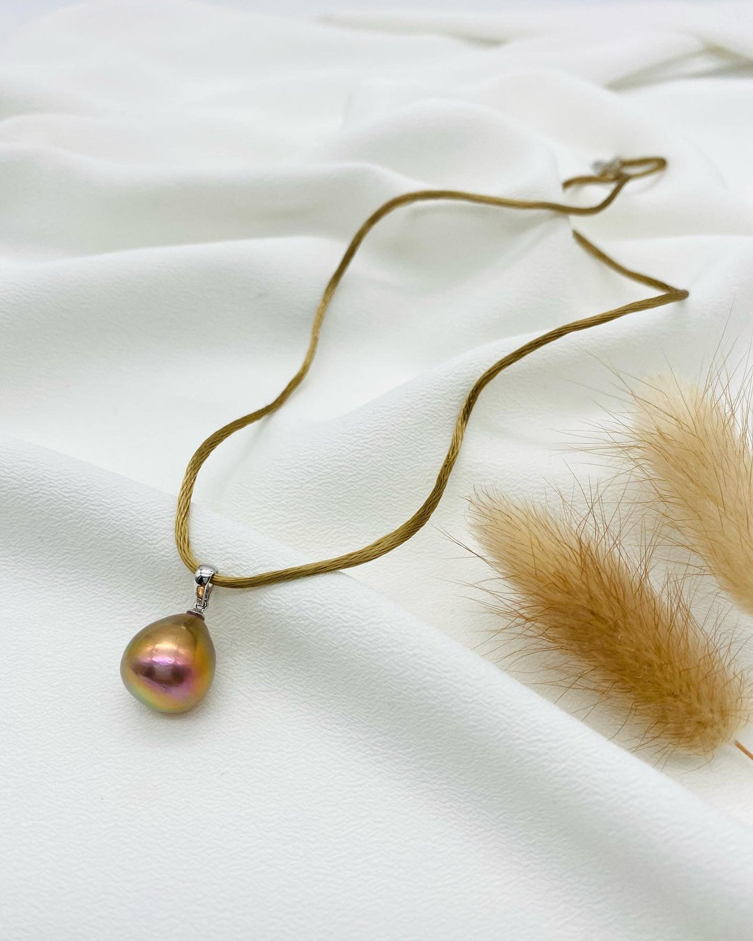 Ming-Perlenanhänger auf hellem Seidenstoff, irisierende Süßwasserperle