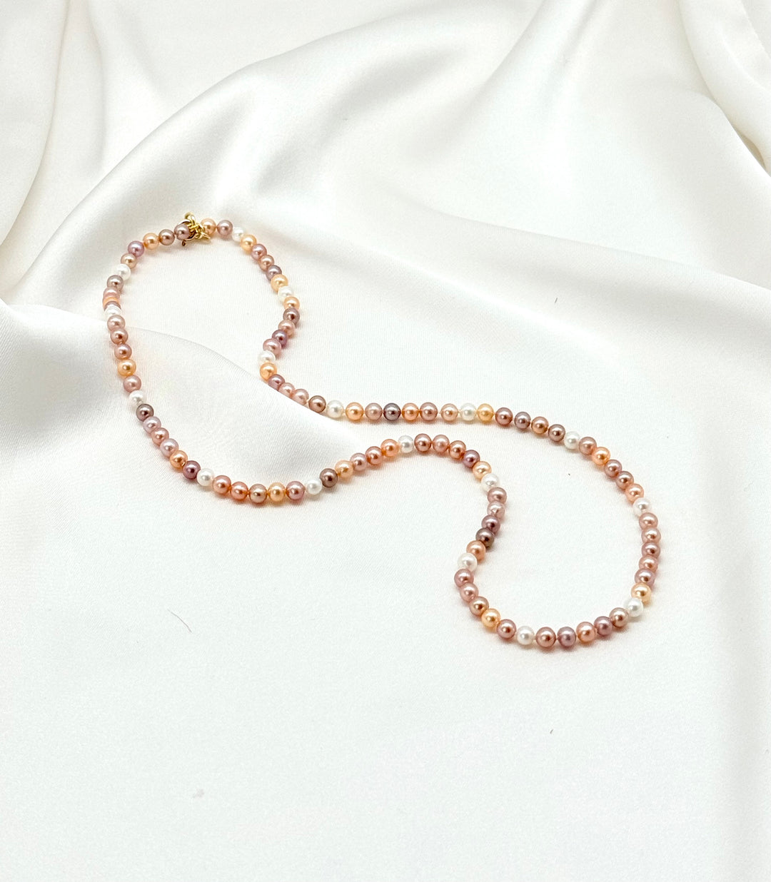 Rosaline Multicolor Perlenkette mit natürlichen Rosé-, Apricot- und Lavendeltönen auf weißem Satin